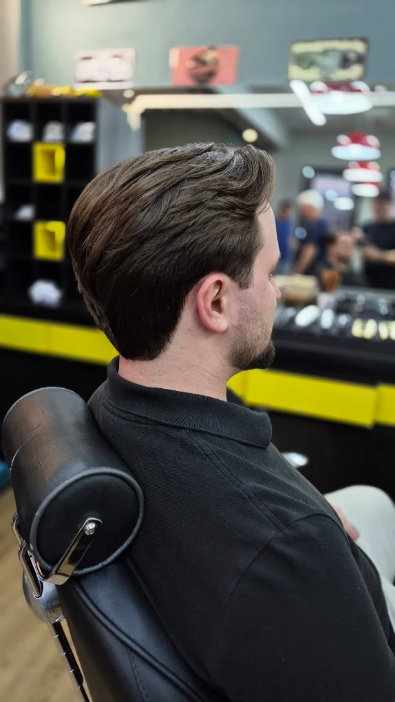 Cliente com corte finalizado na cadeira da barbearia